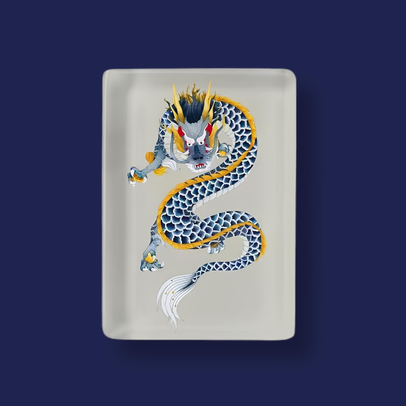 May include: A rectangular white tray featuring a central illustration of a long, serpentine dragon. The dragon has dark blue scales, a yellow spine, and yellow horns. It is depicted in a dynamic, coiled pose with a white tail and sharp claws.