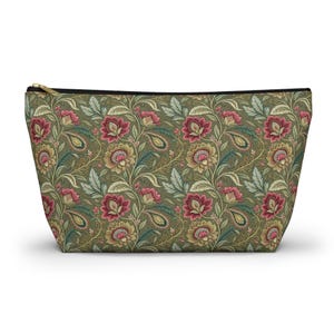 Peut inclure: Une trousse de maquillage zippée avec un motif floral. Le sac présente un motif répété de fleurs rouges, jaunes et vertes et de formes de cachemire sur un fond vert foncé. La fermeture éclair est dorée.