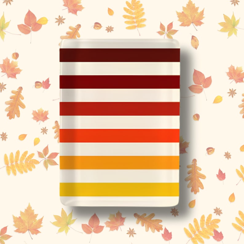 May include: A rectangular ceramic tray featuring horizontal stripes in a gradient of autumn colors, transitioning from dark brown at the top to deep red, bright orange, golden yellow, and light yellow at the bottom, set against a cream background.