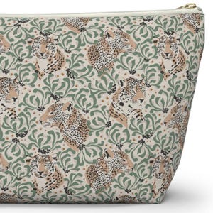 May include: A beige zippered pouch featuring a repeating pattern of stylized jaguar faces and green floral elements. The jaguar's fur is tan with black spots. The pouch has a gold-colored zipper.