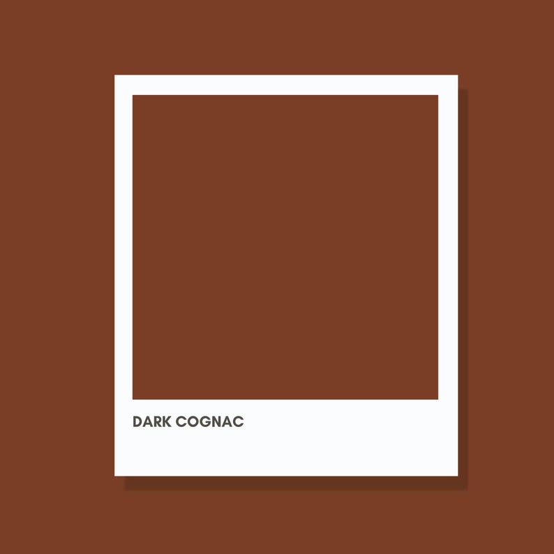 May include: A square-shaped graphic element resembling a classic instant film frame with a solid dark cognac brown center. The white border surrounds the central color block, and the text DARK COGNAC is printed in black at the bottom white margin.