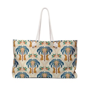 Peut inclure: Grand sac fourre-tout avec un fond crème et un motif répété de palmiers bleus, de léopards oranges et d'éléments floraux. Le sac a des poignées en corde blanche.