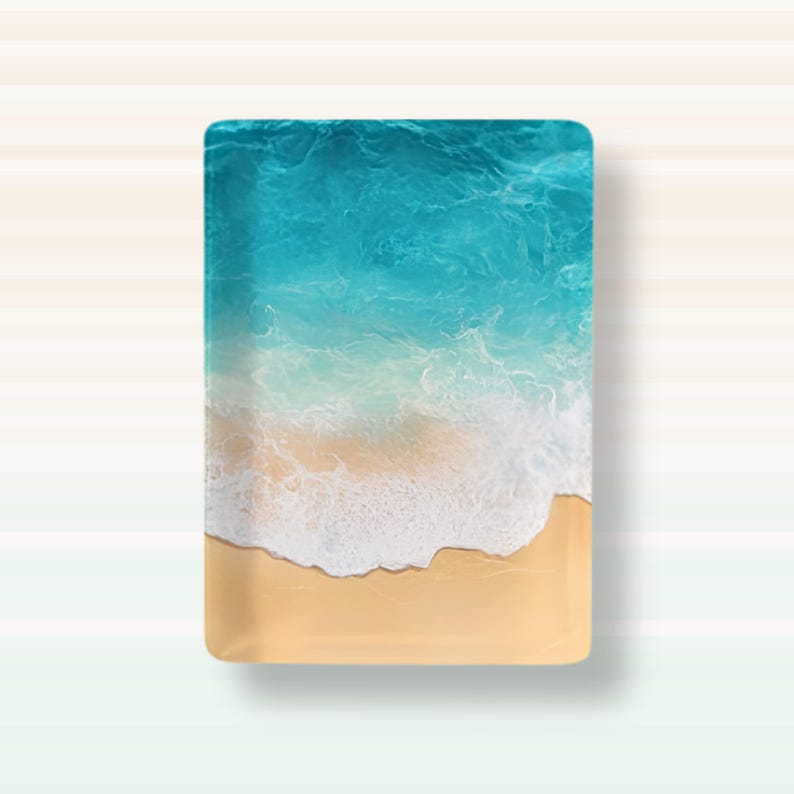May include: A rectangular tray featuring a top-down view of a beach scene. The design displays a smooth, light tan sandy shore at the bottom, transitioning into white, foamy ocean waves, and deep turquoise blue water at the top of the tray.