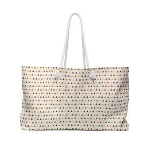 May include: A large tote bag with a cream-colored background and a repeating pattern of small triangles in shades of brown, green, and gold. The bag has white rope handles.