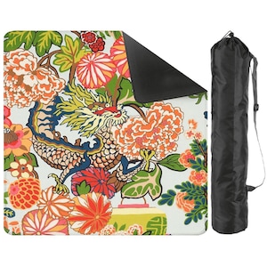 May include: A colorful picnic blanket featuring a dragon design with orange, yellow, and green floral patterns. The blanket has a black underside and comes with a black carrying bag with a shoulder strap.