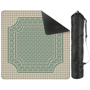 May include: A square outdoor blanket featuring a sage green and cream polka dot border with a central ornate floral pattern in sage green and white. The blanket has a black underside and is accompanied by a black cylindrical carrying bag with a strap.