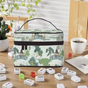 May include: A rectangular cosmetic bag with a top handle and a zip closure, featuring a light green background with a repeating pattern of dark green trees, pagodas, and arched bridges. The bag is surrounded by scattered mahjong tiles.