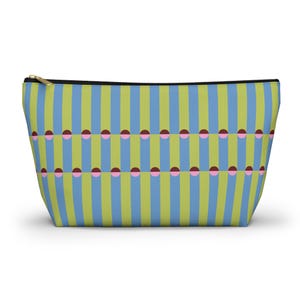 May include: A rectangular cosmetic bag with a gold zip. The bag has a repeating pattern of vertical stripes in light blue and green, with rows of pink and maroon half-circles. The bag is designed to stand upright.
