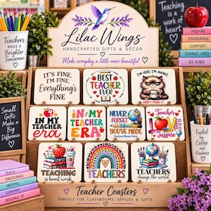 May include: A wooden display stand holding nine square coasters with various teacher-themed designs and text, including phrases like Best Teacher Ever, In My Teacher Era, and Teachers Change the World, alongside decorative items like pencils and a red apple.