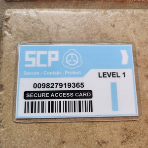 May include: A rectangular, light blue and white secure access card with the text "SCP" and "Secure - Contain - Protect". The card also features a barcode, the number "009827919365", and the words "SECURE ACCESS CARD" and "LEVEL 1".