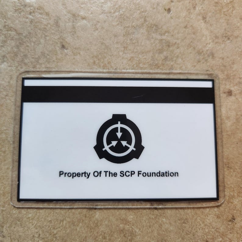 May include: A rectangular card with a clear plastic border. The card has a white background with a black stripe at the top. The card features a black logo and the text "Property Of The SCP Foundation."