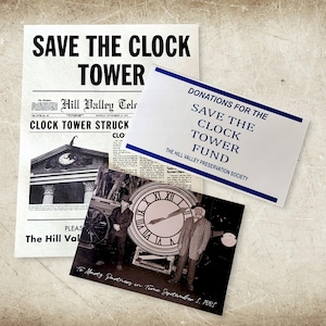 May include: A black and white photo of two people standing in front of a large clock. The clock is on a platform with wheels. The photo is captioned "To Marty Partners in Time September 5, 1985". The photo is accompanied by a newspaper clipping with the headline "Clock Tower Struck" and a sign that reads "Donations for the Save the Clock Tower Fund. The Hill Valley Preservation Society."