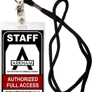 Puede incluir: Una placa de identificación de personal en blanco y negro con el texto "STAFF" y "ARKHAM INSTITUTE FOR THE CRIMINALLY INSANE". La placa también tiene el texto "AUTHORIZED FULL ACCESS" en rojo y un código de barras con el número "34285692670". La placa está unida a un cordón negro con un clip plateado.