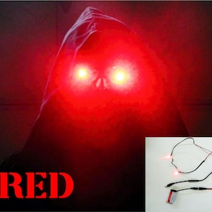 May include: A dark image of a hooded figure with bright red eyes and the word "RED" in red. A small inset shows a battery-powered LED light setup with two red lights.