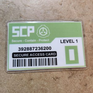May include: A rectangular Secure Access Card with a green and white design. The card features the letters "SCP" in large, bold letters, along with the words "Secure - Contain - Protect." It also displays "LEVEL 1," a barcode, and the text "SECURE ACCESS CARD."