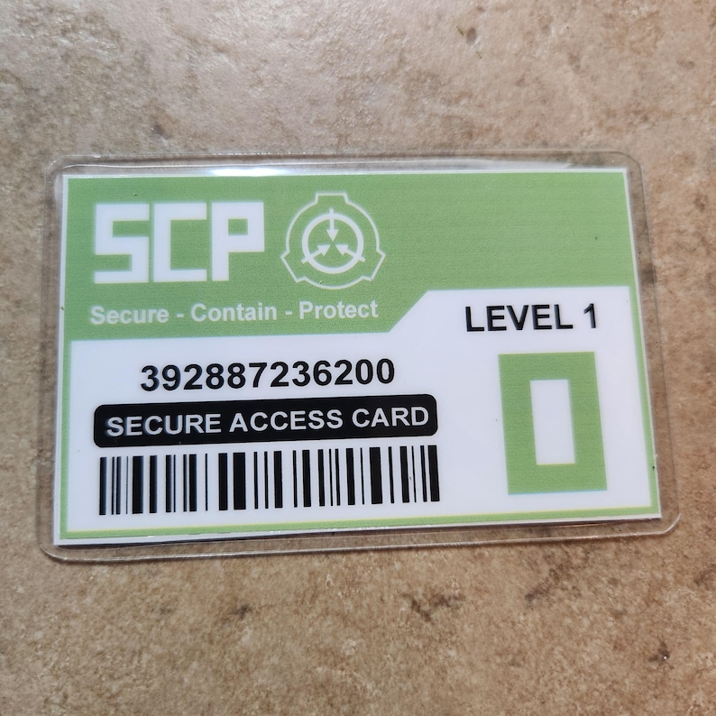 May include: A rectangular Secure Access Card with a green and white design. The card features the letters "SCP" in large, bold letters, along with the words "Secure - Contain - Protect." It also displays "LEVEL 1," a barcode, and the text "SECURE ACCESS CARD."