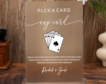 May include: A brown card with the text "PLCK A CARD any card" and a graphic of playing cards. The card is displayed in a clear acrylic stand. The text "Rachel + Jack" is at the bottom.