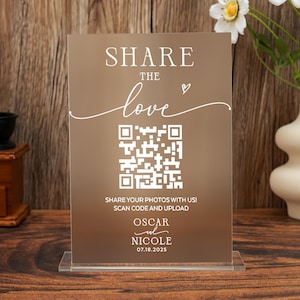 Peut inclure: Panneau acrylique transparent avec le texte "SHARE THE love" et un code QR. En dessous, il est écrit "SHARE YOUR PHOTOS WITH US! SCAN CODE AND UPLOAD" avec les noms "OSCAR & NICOLE" et la date "07.18.2025".