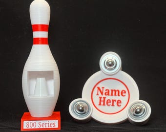 May include: A white and red bowling pin with a red base that reads "800 Series." Next to it is a white spinner with three silver bearings and the text "Name Here" in a red circle.