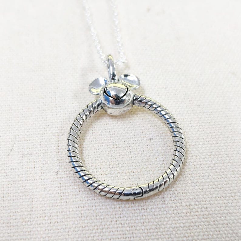 Op de afbeelding: Een witte keramische mok met een zwarte handgreep en de tekst "But First, Coffee" in een vetgedrukte, zwarte letter. De mok is gevuld met een donkere vloeistof, waarschijnlijk koffie, en staat op een lichtgekleurd oppervlak.