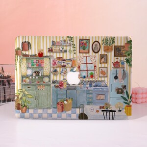 May include: A decorative laptop case featuring a whimsical kitchen scene. The design includes a green cabinet, blue appliances, and various kitchen items. The background has yellow and white striped wallpaper, with a pink background.