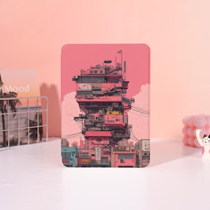 May include: A pink tablet case featuring a detailed illustration of a multi-story building with a complex design. The artwork includes various architectural elements, antennas, and Japanese text, set against a pink sky.