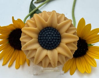 Pastilla de jabón con forma de girasol, con manteca de cacao, perfumada con hierba limón, may chang, ylang-ylang y pachulí.