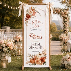 May include: A vertical white banner on a wooden stand featuring the text fall in love, WELCOME TO Olivia's BRIDAL SHOWER, and 10.20.2026. The design includes watercolor illustrations of orange and white pumpkins, autumn leaves, and cream and rust flowers.