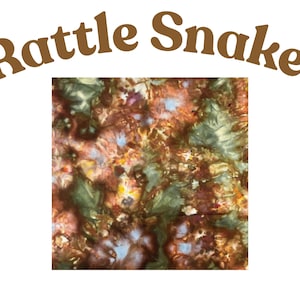 May include: A square fabric swatch featuring a tie-dye pattern in shades of brown, dark green, and hints of light blue and yellow. The text "Rattle Snake" is printed in brown letters in an arched formation above the square fabric sample.