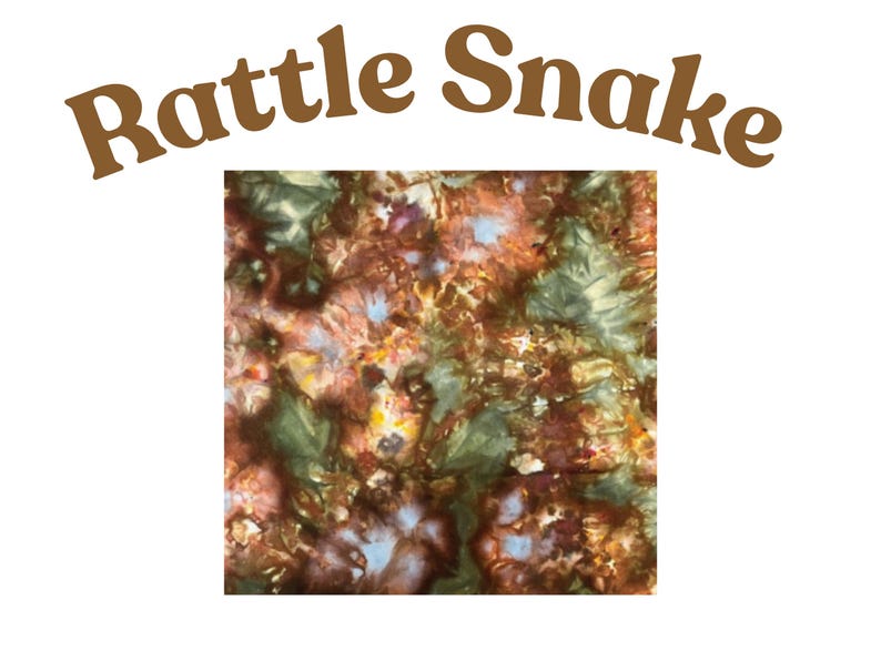 May include: A square fabric swatch featuring a tie-dye pattern in shades of brown, dark green, and hints of light blue and yellow. The text "Rattle Snake" is printed in brown letters in an arched formation above the square fabric sample.
