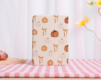May include: A rectangular object featuring a cream backdrop with a repeating pattern of orange pumpkins, white ghosts, and brown bows. The design has a Halloween theme, suitable for seasonal decorations.