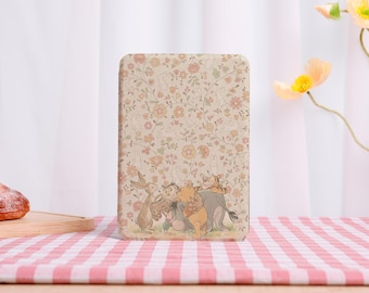 May include: A rectangular, beige case with a floral pattern and cartoon characters. The design includes Winnie the Pooh, Piglet, Tigger, and Rabbit. The case is on a red and white checked tablecloth.