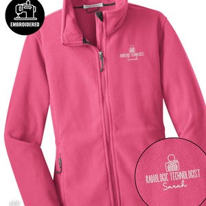 May include: A bright pink fleece jacket with a full-length front zipper and a high collar. The chest features white embroidery with a graphic of a rib cage and the text "RADIOLOGIC TECHNOLOGIST Sarah". A circular inset shows the embroidery detail.