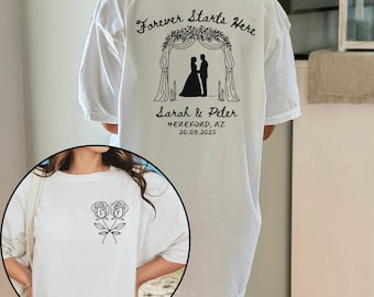 May include: White t-shirt with a black graphic on the back featuring a wedding arch, silhouettes of a couple, and the text "Forever Starts Here." The shirt also includes the names "Sarah & Peter" and the date 20.09.2025.
