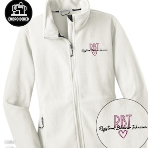 May include: A white fleece jacket with a full zipper and a stand-up collar. The jacket features the embroidered text "RBT Registered Behavior Technician" with a heart symbol. The jacket also has the text "Winter White".