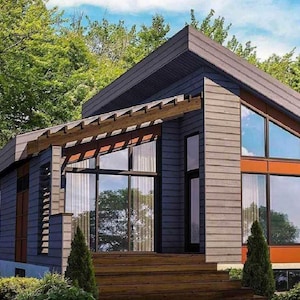 Puede incluir: Una casa moderna con exterior azul oscuro, grandes ventanas con marcos naranjas y una terraza de madera. El tejado es gris oscuro, rodeado de árboles y zonas verdes.