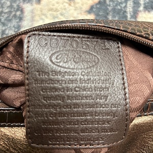 May include: A rustic wooden sign with the text "Welcome" in a handwritten style. The sign is painted white with a distressed finish, and features a decorative floral design in the corner. The background is a blurred image of a wooden surface.