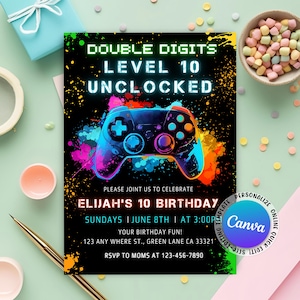 Może przedstawiać: Czarna zaproszenie z kolorową grafiką kontrolera do gier wideo. Tekst brzmi "Double Digits Level 10 Unlocked" i "Elijah's 10 Birthday". Zawiera datę, godzinę, adres i informacje RSVP. Zabawny projekt na przyjęcie urodzinowe.
