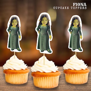 Puede incluir: Tres cupcakes con glaseado blanco, cada uno coronado con un adorno para cupcakes de Fiona. Los adornos presentan una imagen de dibujos animados de Fiona con un vestido verde. El texto "FIONA CUPCAKE TOPPERS" está impreso encima de los cupcakes.