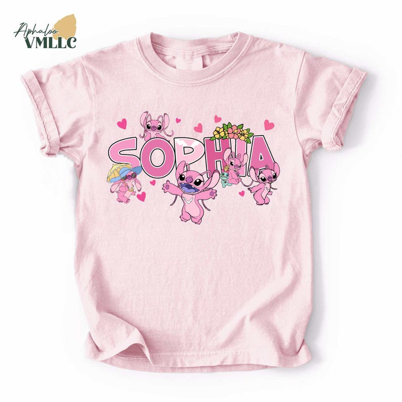 A pink t-shirt with a design featuring the characters from the Disney movie "Stitch". The characters include a pink bunny, a pink cat, and a pink dog, along with the name "Sophia" written in pink letters.