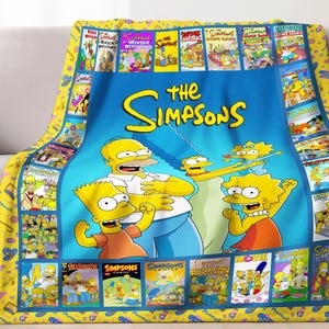 May include: A blue blanket featuring the Simpsons family with the words "The Simpsons" in yellow. The blanket has a yellow border with comic book covers. The Simpsons characters include Homer, Marge, Bart, and Lisa.