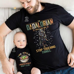 A man and a baby wearing matching t-shirts with a graphic design featuring a character from the Star Wars franchise.