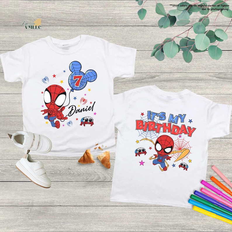 two white t-shirts with Spiderman designs, one with the number 7 and the other with the text "It's My Birthday". The t-shirts are displayed on a wooden surface, along with some children's shoes and a pair of crayons.