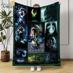 May include: A green and black fleece blanket featuring a collage of images from the movie "Alien." The design includes scenes of the alien creature, characters in space suits, and the movie title. The blanket is held up by a person.