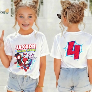 K&ouml;nnte beinhalten: Wei&szlig;e T-Shirts mit einer farbenfrohen Grafik mit Spider-Man-Charakteren und dem Text "JAXSON AND AMAZING FRIENDS". Auf der R&uuml;ckseite des Shirts ist die rote Zahl 4 in einem blauen Spinnennetz-Design abgebildet. Die Shirts werden von einer jungen Person getragen.