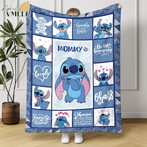 May include: A blue and white throw blanket featuring the character Stitch from Lilo & Stitch. The blanket has a patchwork design with Stitch in various poses, along with the words "Ohana", "Family", and "Mommy".