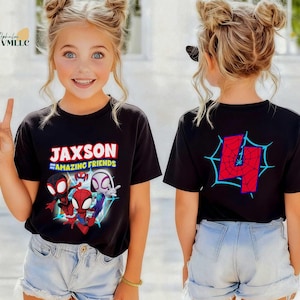 K&ouml;nnte beinhalten: Schwarzes T-Shirt mit dem Text "Jaxson and Amazing Friends" und Cartoon-Spider-Man-Figuren. Auf der R&uuml;ckseite des T-Shirts befindet sich die rote Zahl 4 in einem blauen Spinnennetz-Design. Kombiniert mit Jeansshorts.