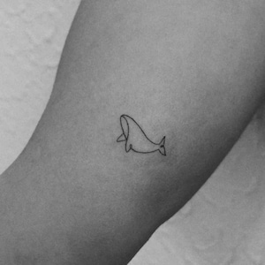 Könnte beinhalten: Ein kleines Tattoo mit schwarzer Tinte, das eine durchgehende Linienzeichnung eines Wals zeigt. Das Design besteht aus einer einfachen, minimalistischen Kontur, die die Form des Walkörpers, des Kopfes und der Schwanzflosse auf der Haut nachbildet.