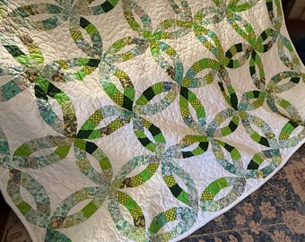 May include: A white quilt with a green and white floral pattern. The quilt is made in a double ring pattern.