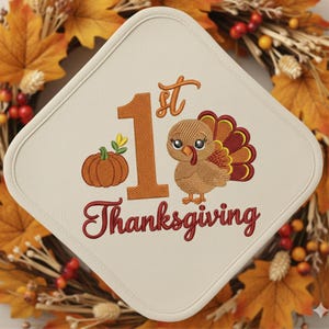 May include: A diamond-shaped off-white fabric potholder featuring an embroidered design with the text 1st Thanksgiving in orange and red. The embroidery includes a small orange pumpkin and a brown cartoon turkey with colorful tail feathers.